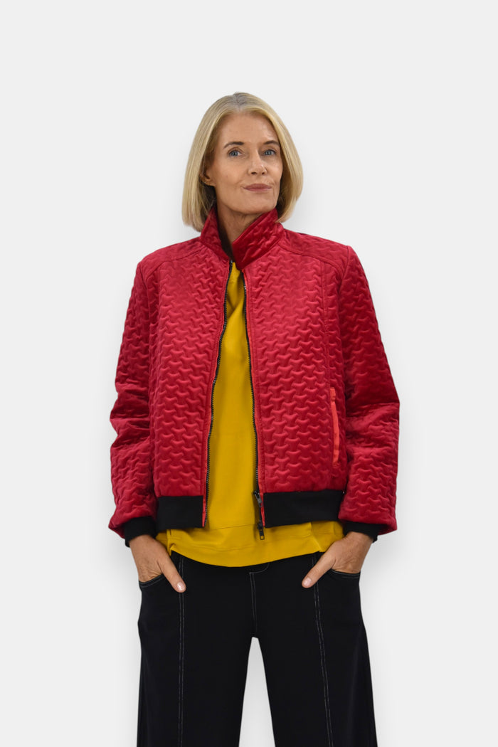 Woman wearing a red quilted jacket over a yellow top on a white background